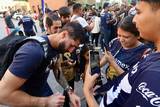 Se observa a un jugador del pumas firmando una camiseta